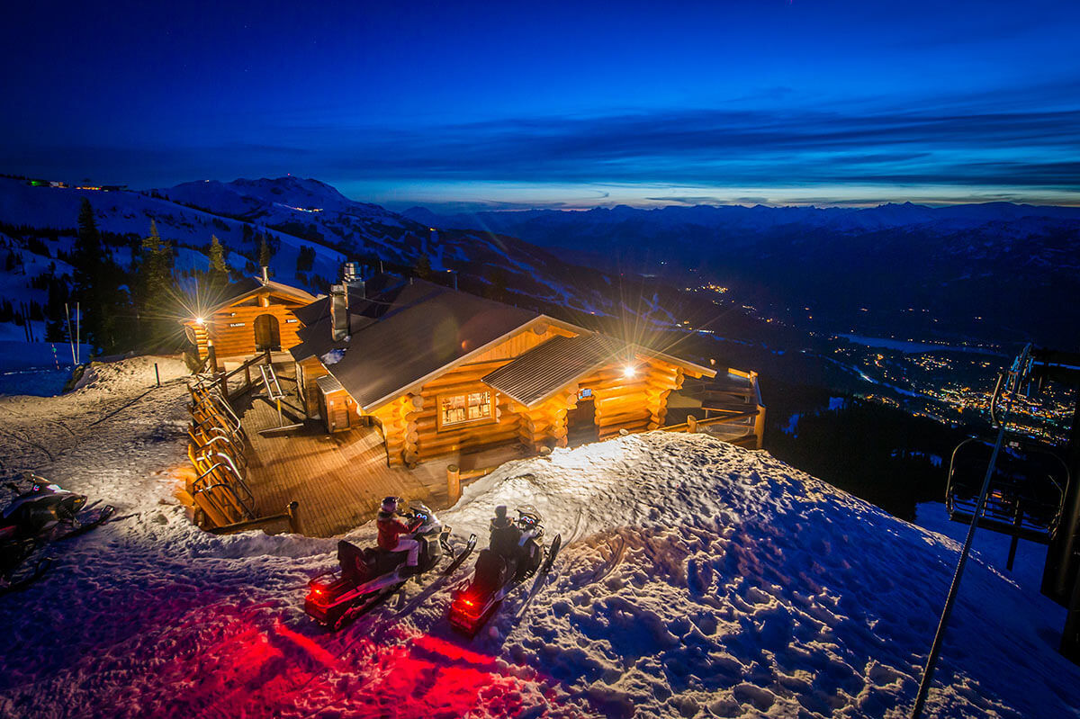 The Crystal Hut log cabin on Blackcomb Mountain surrounded by snow at dusk
