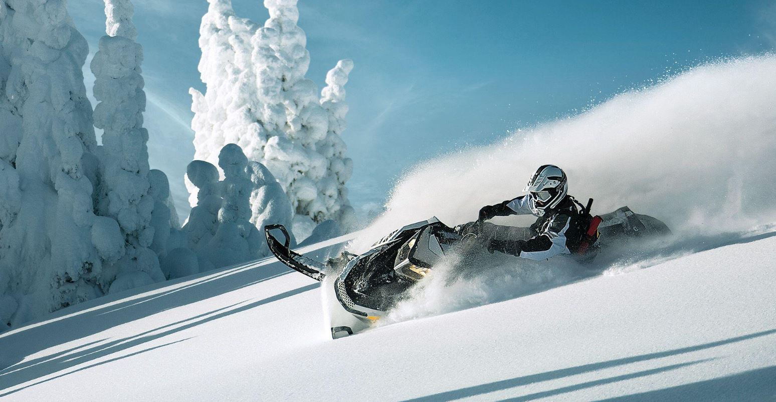 Snowmobilers riding across an open alpine bowl above the treeline near Whistler