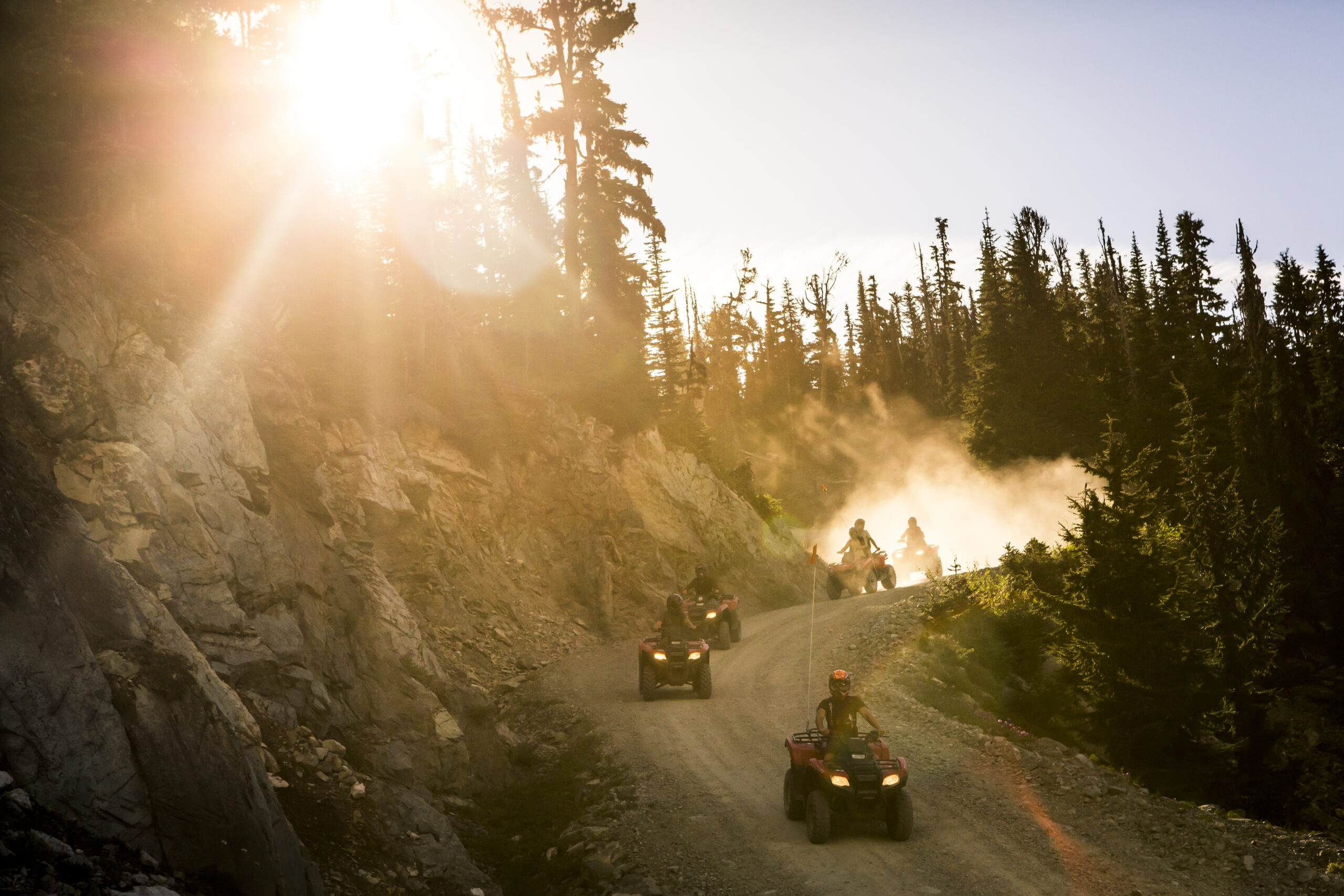 Riders on ATVs climbing a forest trail on Blackcomb Mountain above Whistler