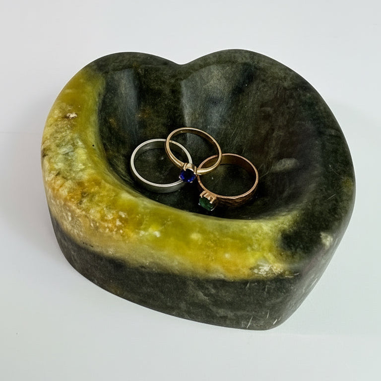 A hand-carved green and gold soapstone bowl holding rings, made in a carving class