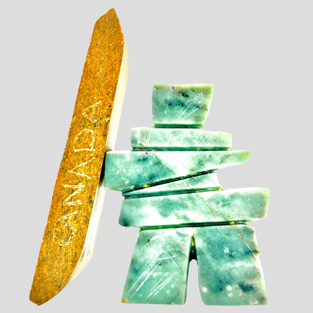A carved green soapstone Inukshuk beside an engraved stone bar reading Canada