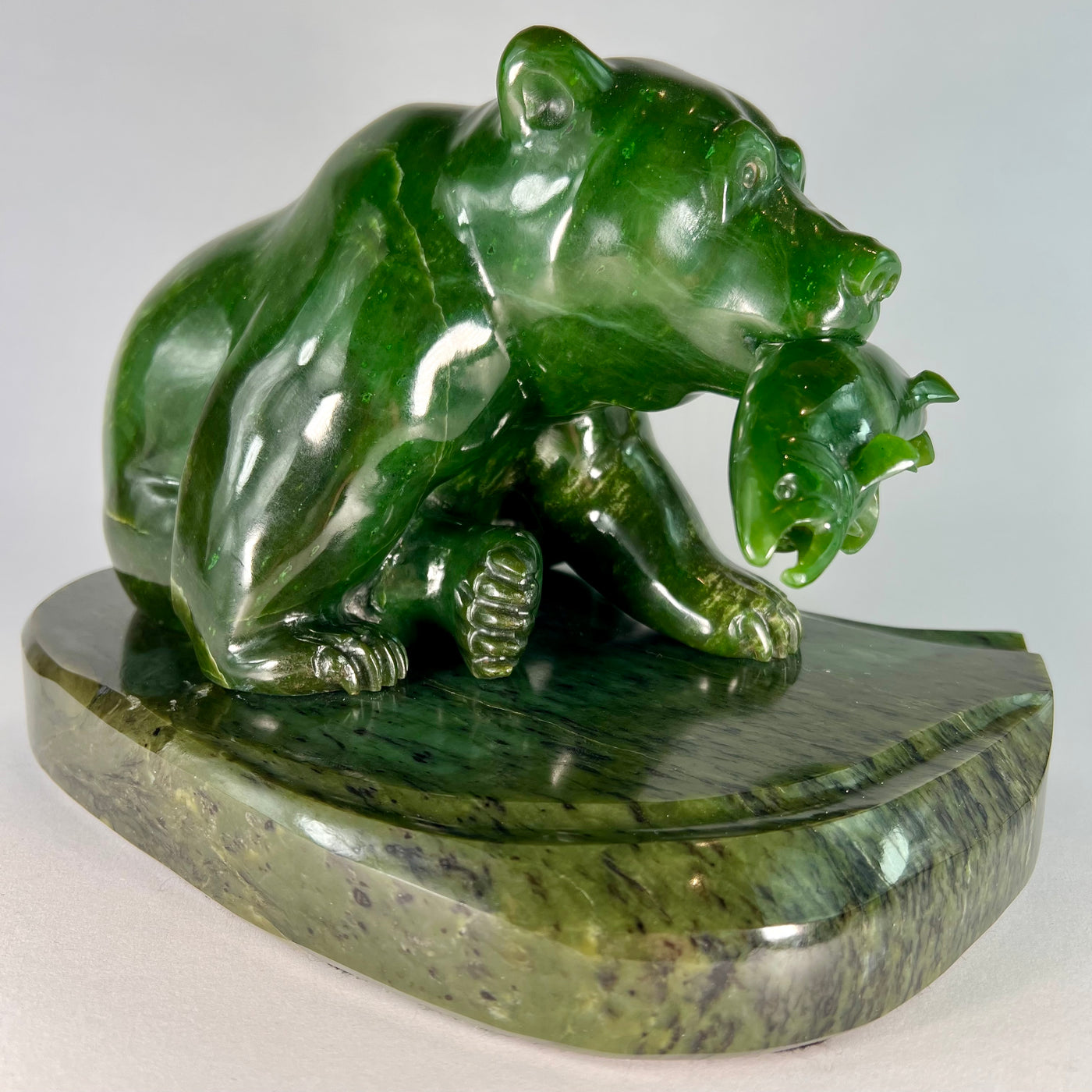 A deep green British Columbia jade bear sculpture holding a fish