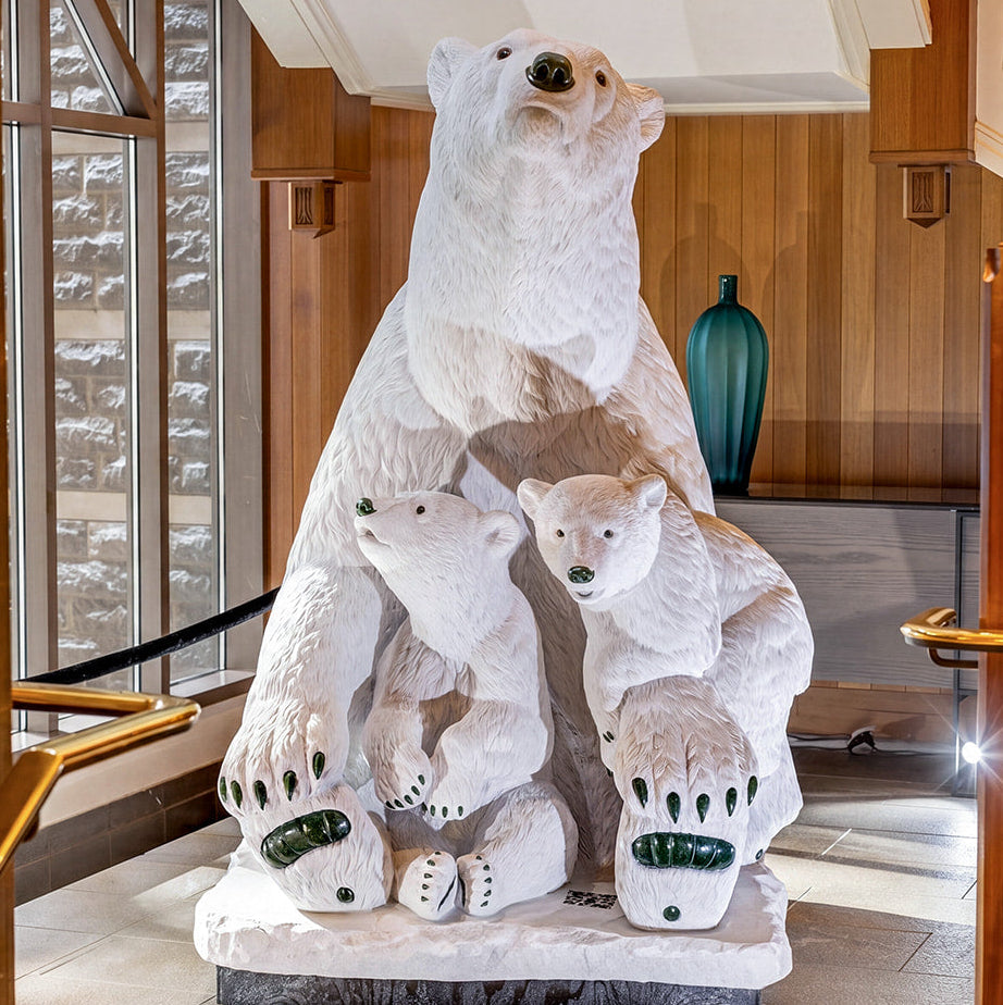 A life-size white marble polar bear with two cubs carved by Fathom Stone Art