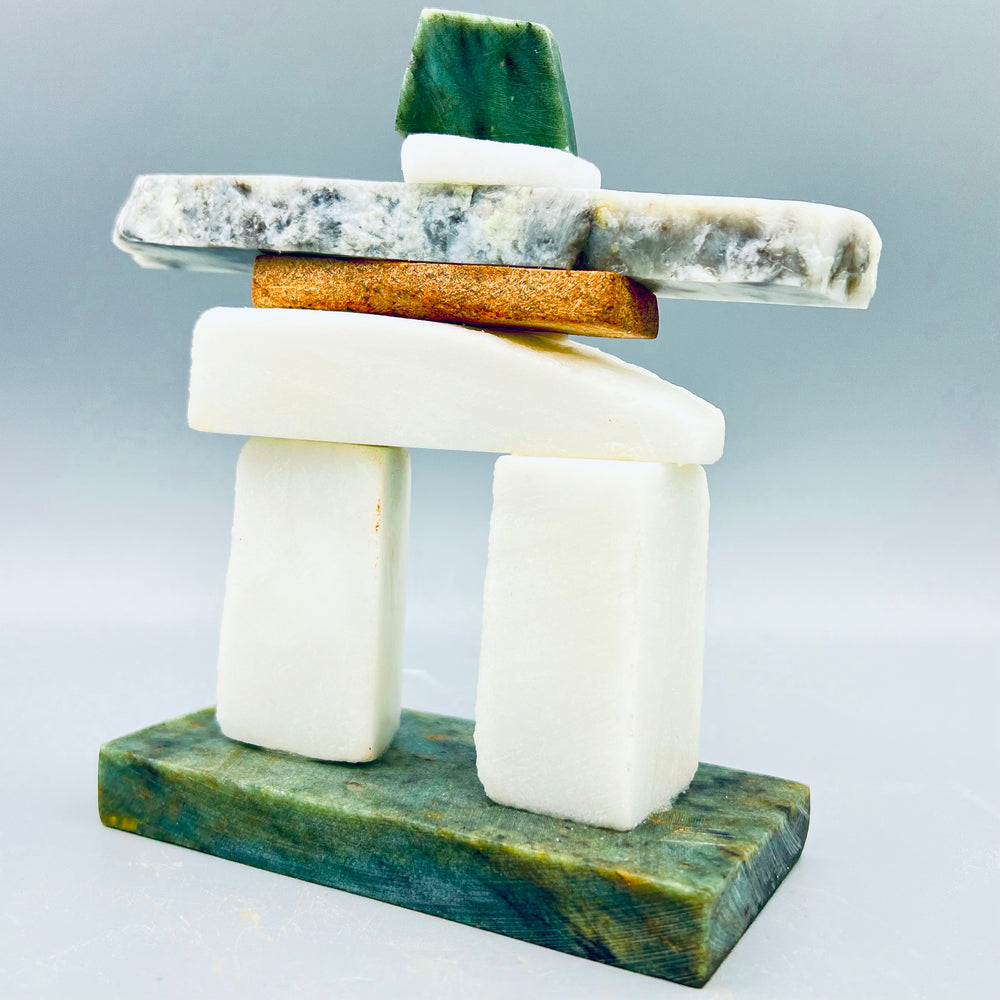 A stacked Inukshuk built from white, grey and green stone pieces on a jade base