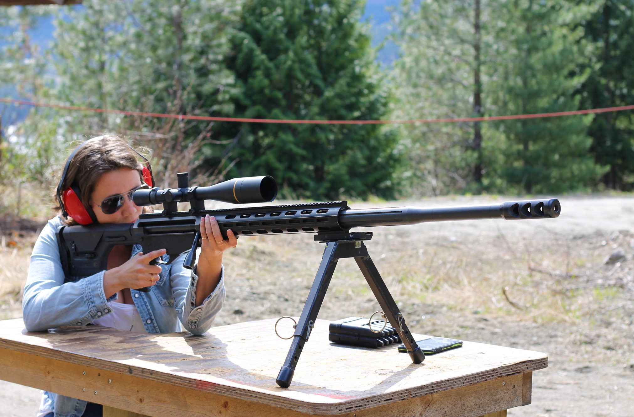 A shooter at the outdoor range at Whistler Shooting Adventures with mountains behind