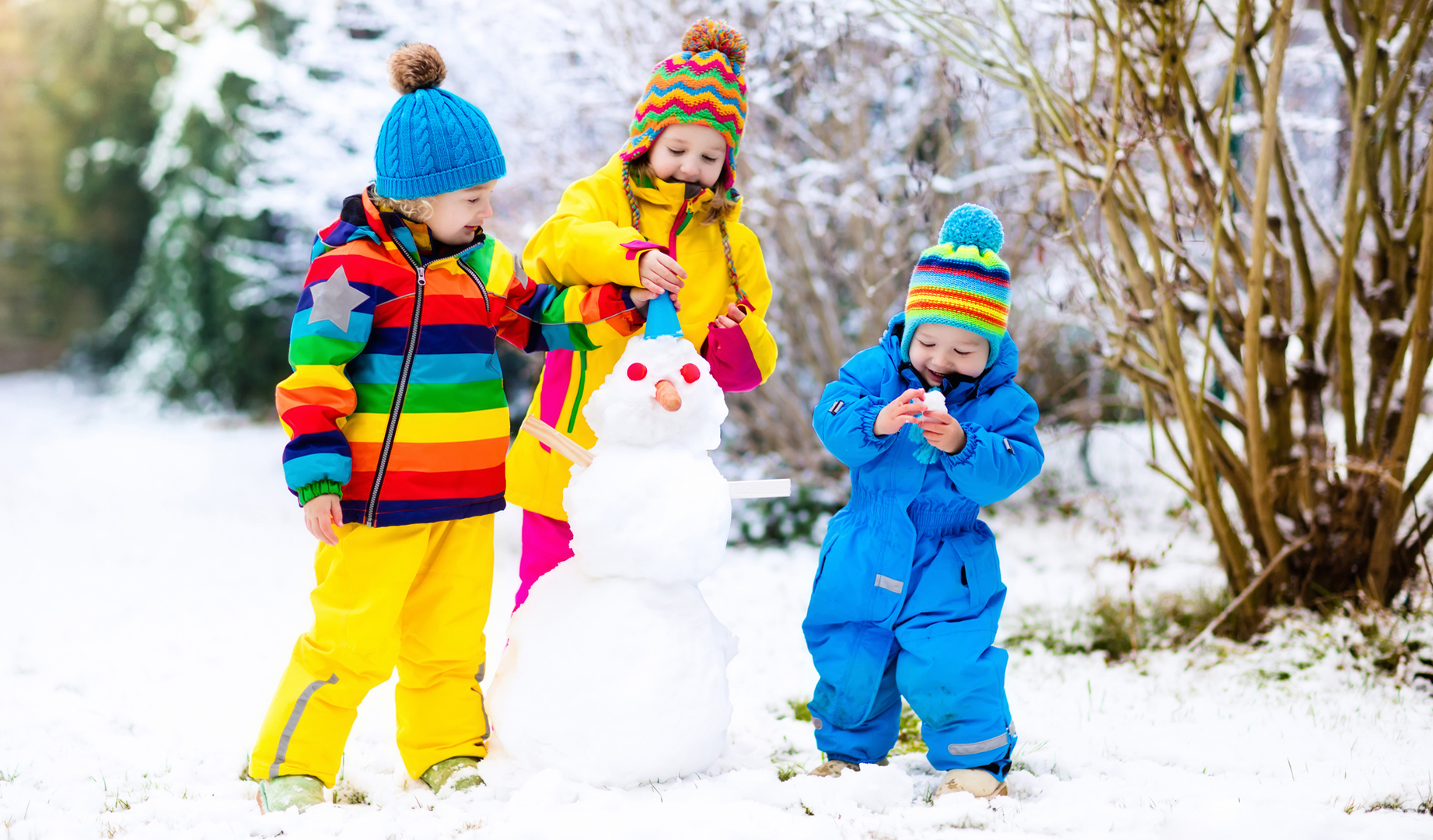 Children playing in the snow in Whistler with the mountains behind
