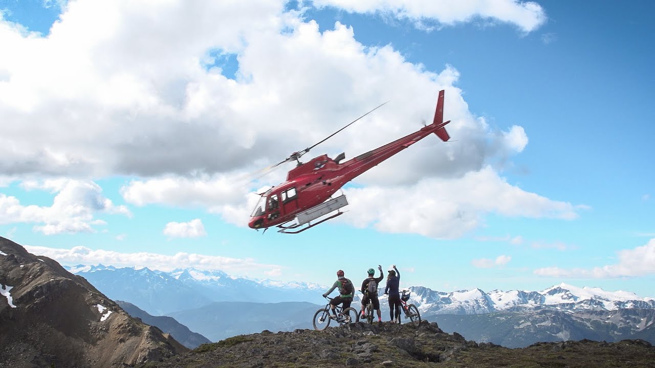 A mountain biker unloading from a helicopter on an alpine ridge near Whistler