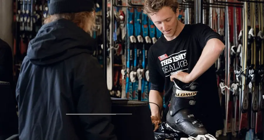 A rental technician fitting a ski boot in a Whistler shop