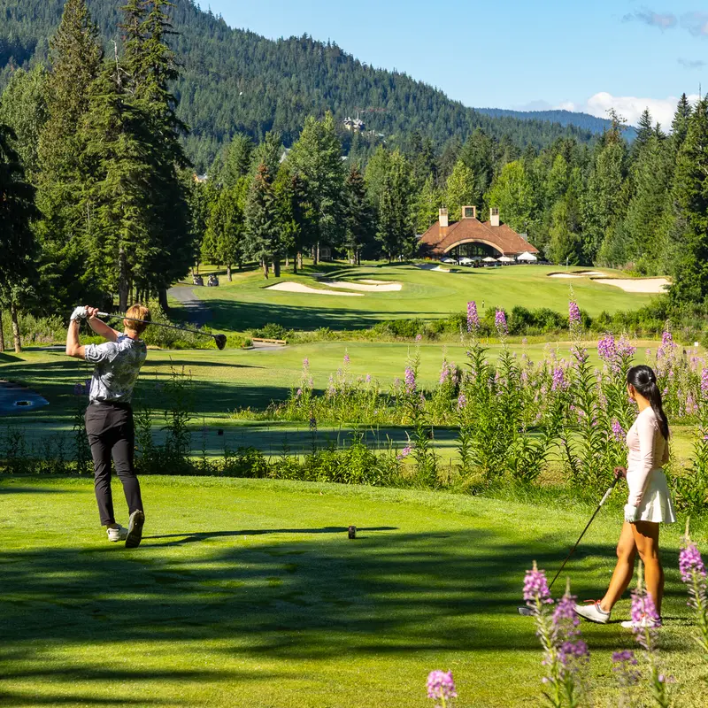 Golfers teeing off among wildflowers at the Fairmont Chateau Whistler course